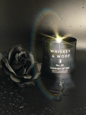 Get to know whiskey & woof scented candles. Photo of Summer of Sex Candle next to a black rose. The scent is bergamot, ambergris & oud. 